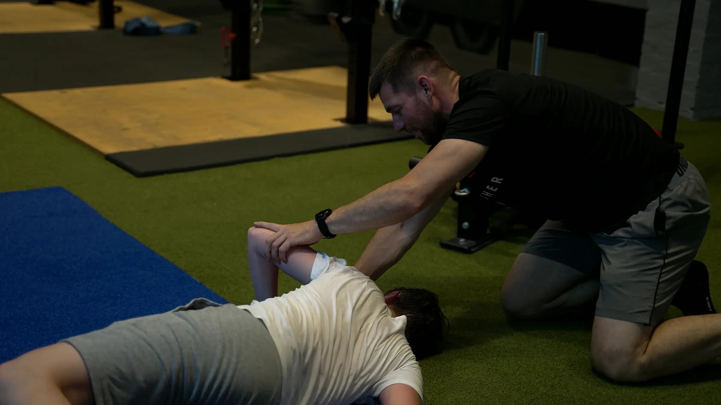 Trainer unterstützt einen Jugendlichen bei einer Dehnübung im Jugend-Athletik-Training im Iron Gym Viersen