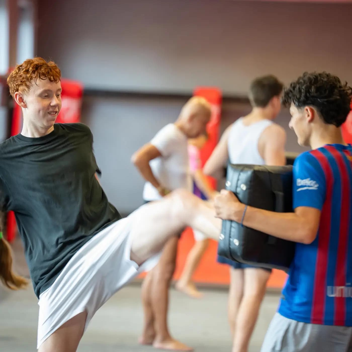 Jugend-Kampfsport im Iron Gym Viersen: Ein Jugendlicher trifft mit dem Knie das Schlagpolster seines Trainingspartners, im Hintergrund weitere Jugendliche im Training