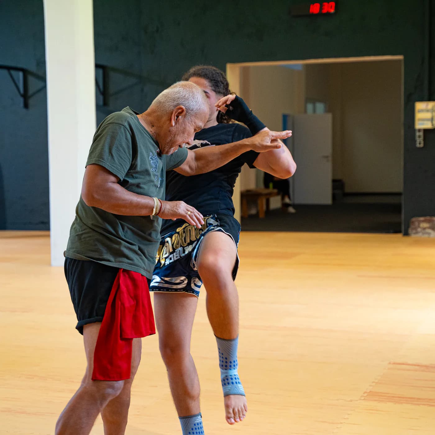 Thaiboxen im Iron Gym: Der Trainer hält den Clinch, die Sportlerin setzt einen Knietritt an
