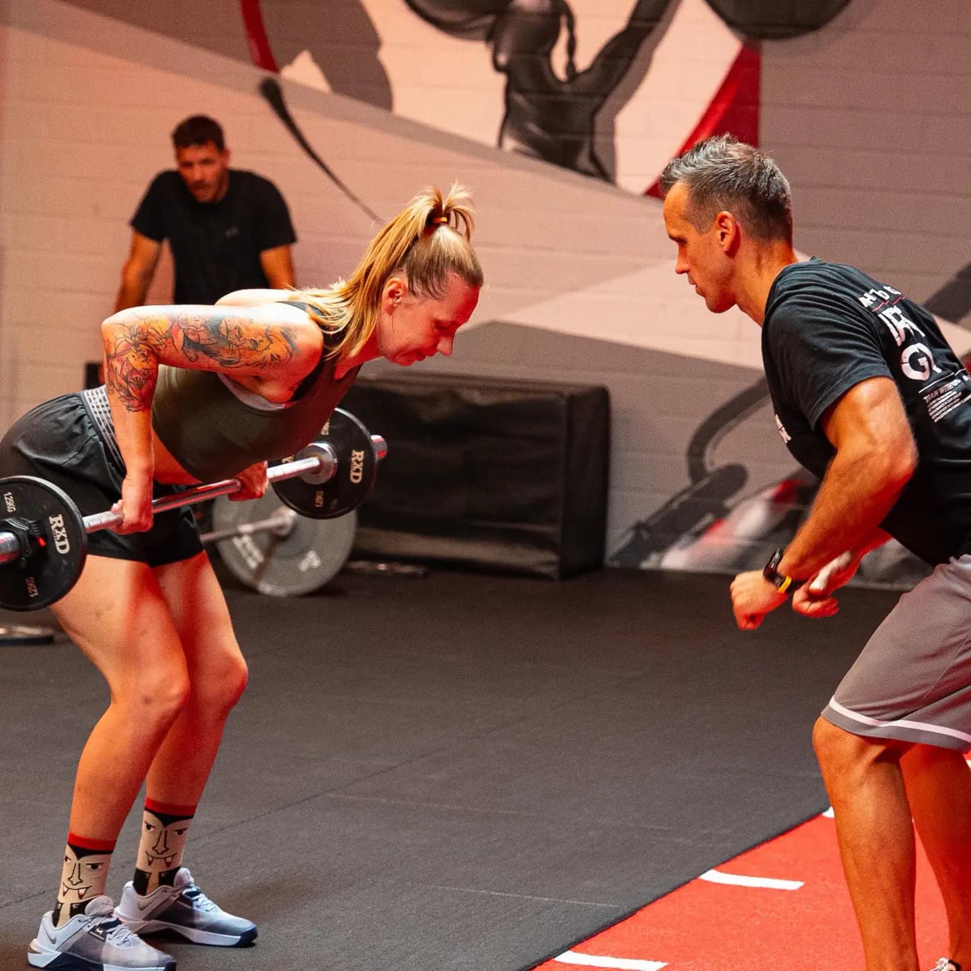 Lady Athletics im Iron Gym Viersen: Teilnehmerin beim vorgebeugten Langhantelrudern, der Trainer korrigiert direkt gegenüber
