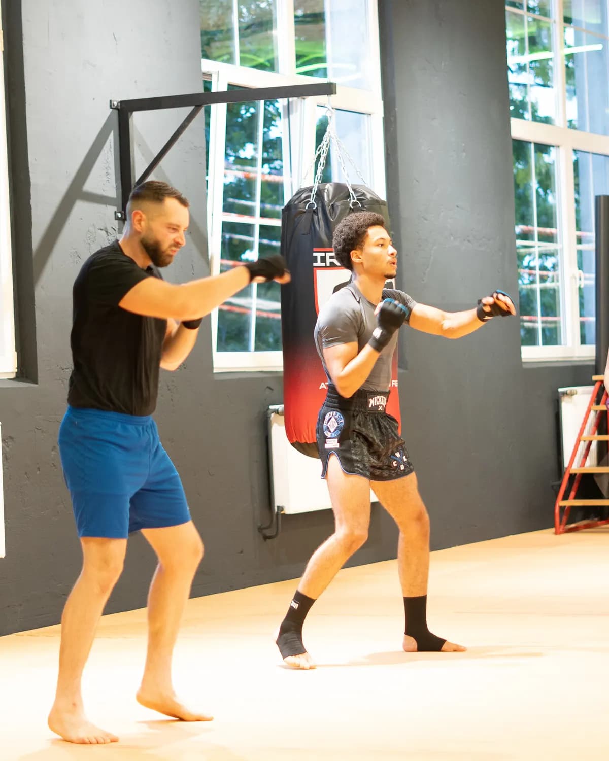 Gruppe trainiert vor dem Boxring des Iron Gym Viersen, links ein Sandsack mit Vereinslogo