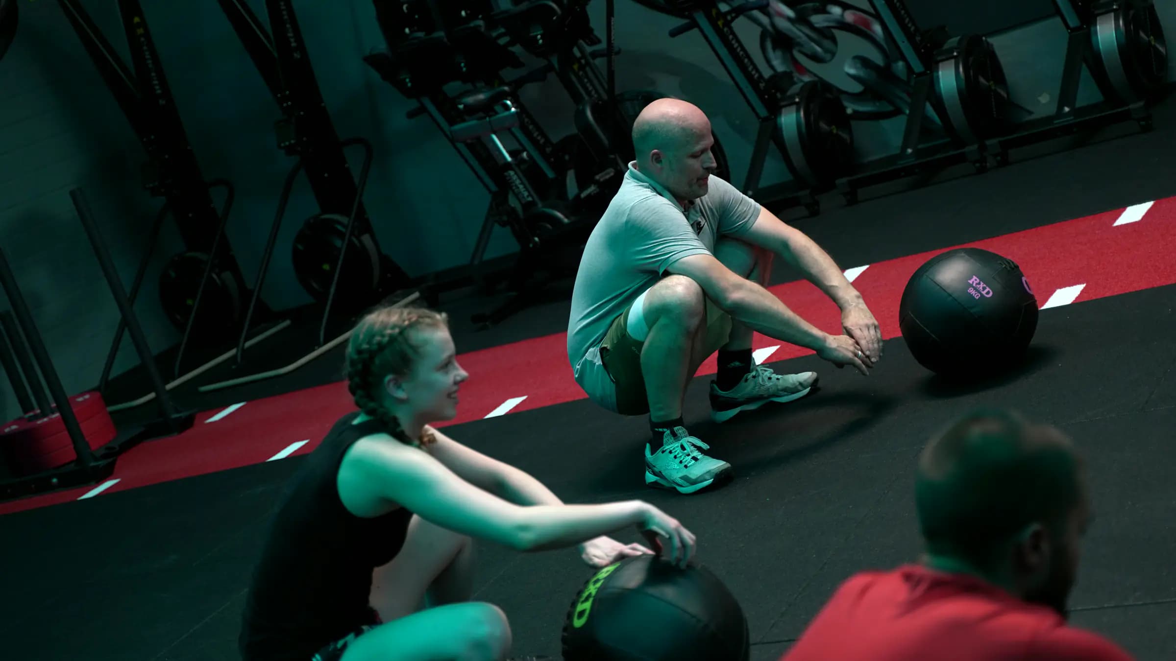 Teilnehmer gehen beim HIIT im Iron Gym Viersen gleichzeitig mit dem Medizinball in die tiefe Hocke